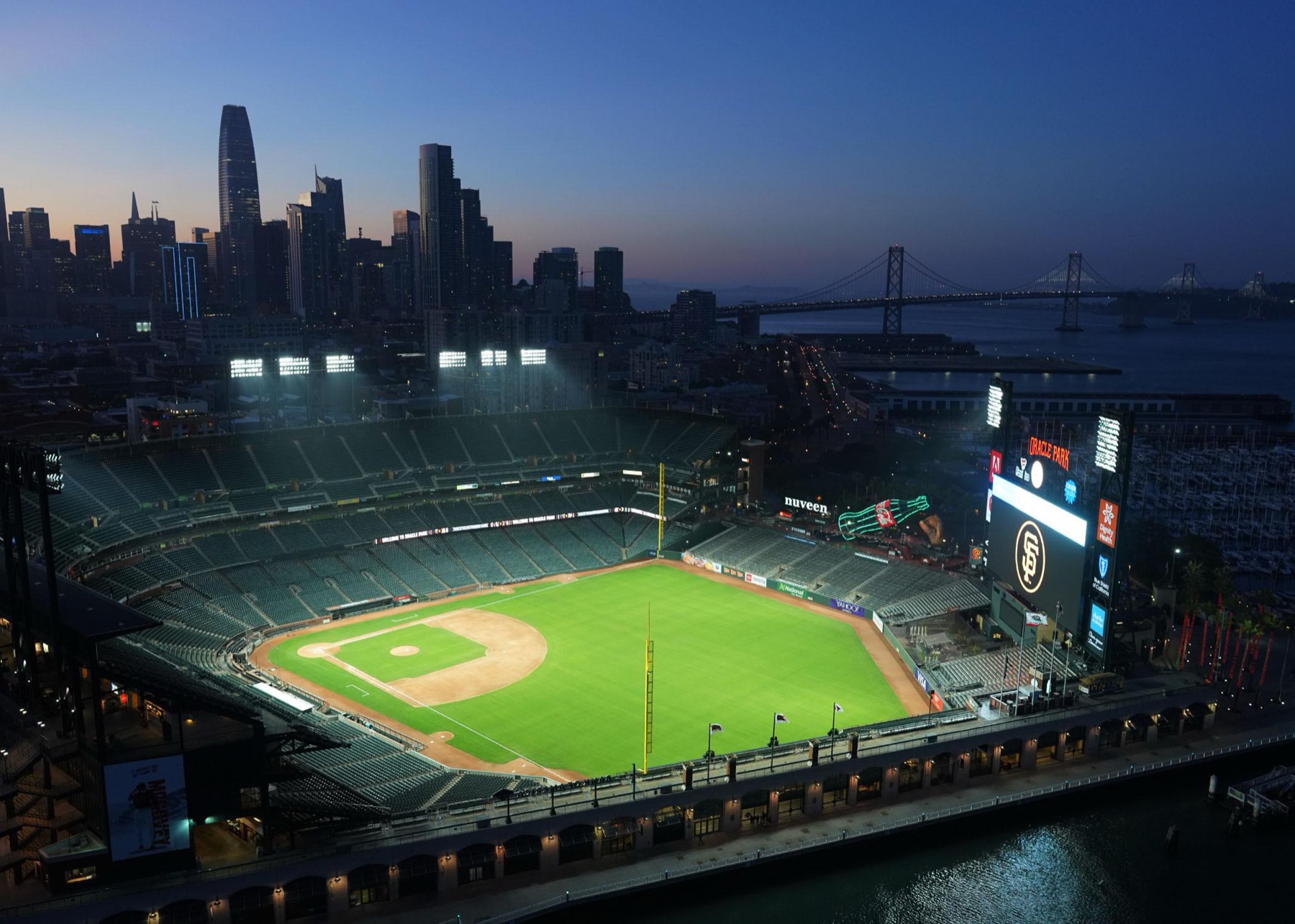 Oracle Park illuminated at night with the San Francisco skyline behind it